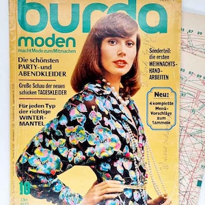 May include: A vintage Burda Moden magazine cover from October 1972, featuring a woman in a floral print blouse and a pearl necklace. The cover has text in German, including "PARTY-und ABENDKLEIDER" and "WINTER-MANTEL".