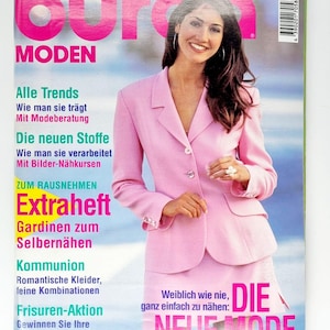 May include: A magazine cover featuring a woman wearing a pink blazer and skirt. The magazine is titled "Burda MODEN" and features the text "Die neue Mode" in large, pink letters.