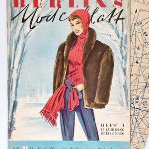 May include: A vintage magazine cover featuring a woman wearing a brown fur coat, a red scarf, and a red hat. The magazine is titled "Berlins Modeblatt" and the text "HEFT 1 15. JAHRGANG PREIS DM 1.50" is visible. The magazine cover is set against a snowy background.
