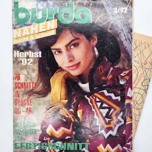 Pode incluir: Uma capa de revista Burda vintage com uma mulher com um casaco estampado. A capa inclui texto em alemão, com "Burda" em verde e amarelo. A revista é de Herbst '92 e inclui padrões de costura.