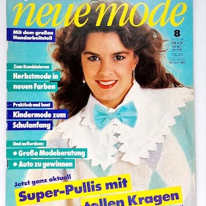 Könnte beinhalten: Ein Magazincover mit einer Frau mit braunen Haaren, die einen weißen Pullover mit einer blauen Schleife trägt. Das Magazin heißt "neue mode" und hat den Text "Super-Pullis mit tollen Kragen" unten.