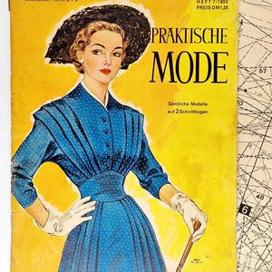 Pode incluir: Uma capa de revista vintage com uma mulher vestindo um vestido azul com bolinhas brancas e um chapéu preto. A revista é intitulada "Praktische Mode" e o texto "Sämtliche Modelle auf 2 Schnittbogen" está impresso abaixo do título.