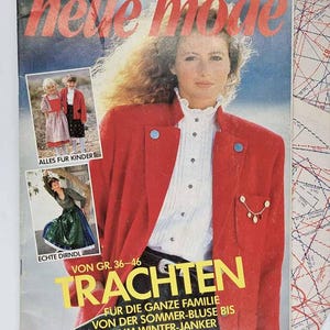 May include: A vintage magazine cover with the title "neve mode" in red. The cover features a woman in a red jacket and white blouse. There are also images of children's clothing and traditional dresses. The text includes "TRACHTEN" and "ALLES FUR KINDER".