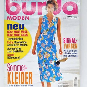 Puede incluir: Portada de la revista "burda MODEN" con una mujer en un vestido azul floral. Número 5/97. El texto en alemán anuncia vestidos de verano y nuevas tendencias de moda, con detalles en rosa y amarillo.