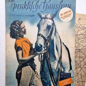 May include: A vintage magazine cover with a woman in an orange top and tan trousers, alongside a white horse. The title reads "Die praktische Hausfrau". Additional text includes "Mit 3000 Mk Preis-Ausschreiben!" and "65 PFENNIG".