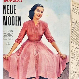 May include: A vintage magazine cover showing a woman in a pink dress with a button-down bodice and full skirt. The magazine title reads "NEUE MODEN" with German text. Sewing patterns are visible in the background.
