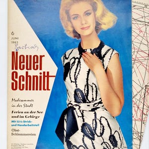 May include: A vintage sewing pattern cover featuring a woman in a white and black dress with a blue sash. The cover has the text "Neuer Schnitt" and "Modesommer in der Stadt Ferien an der See und im Gebirge".