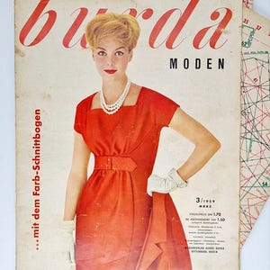 Może przedstawiać: Okładka magazynu vintage "Burda Moden" z kobietą w czerwonej sukience, perłowym naszyjniku i białych rękawiczkach. Tytuł jest czerwony. Okładka zawiera tekst w języku niemieckim i datę marzec 1959. Magazyn mody.