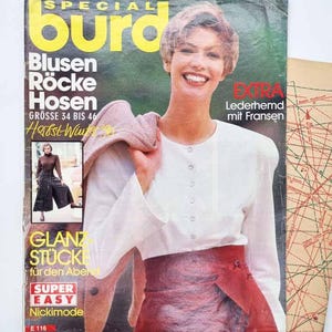 May include: A vintage Burda Special magazine cover featuring a person wearing a white long-sleeved button-down shirt and a dark red skirt. The cover includes text such as Blusen Röcke Hosen, Herbst Winter 90, and Extra Lederhemd mit Fransen.