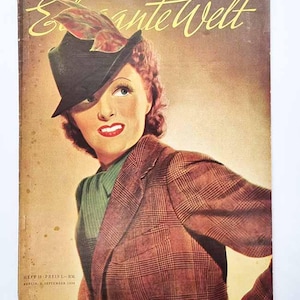 Puede incluir: Portada de revista vintage con una mujer con sombrero y chaqueta a cuadros. El título de la revista "Elegante Welt" está en escritura dorada. La portada tiene un tono sepia con texto en la parte inferior.