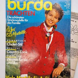 May include: A vintage magazine cover featuring a woman in a red knit jacket. The magazine title is "Burda Special Trachten" in yellow and red. Text includes "Over 50 Models" and "Country-Look". A pattern sheet is visible.