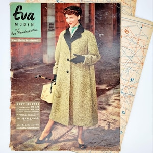 May include: A vintage magazine cover featuring a woman wearing a beige coat with a black fur collar and black gloves. The magazine is titled "Eva MODEN mit Eva Handarbeiten" and has the text "Zwei Hefte in einem!" printed on the cover. The magazine cover also includes the text "HEFT 10/1954 DM 1,50 EVA-VERLAG GmbH. Alle Modelle auf den eveilarbig. Scdinitibegen".