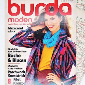 May include: Vintage Burda Moden magazine cover featuring a woman in a colorful plaid jacket, blue scarf, and yellow top. The magazine cover has the Burda Moden logo in red and includes text about sewing patterns and fashion.