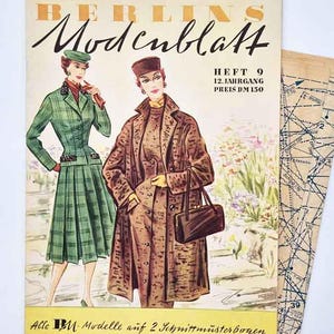Pode incluir: Uma capa de revista vintage Berlins Modenblatt com duas ilustrações de pessoas com agasalhos sob medida. Uma veste um terno xadrez verde com chapéu combinando, enquanto a outra usa um casaco marrom texturizado e carrega uma bolsa escura.