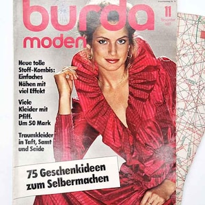 May include: A vintage magazine cover with a woman in a red dress. The magazine title "burda moden" is in large pink letters. Text on the cover includes "75 Geschenkideen zum Selbermachen" and "November 1981". A pattern sheet is visible.