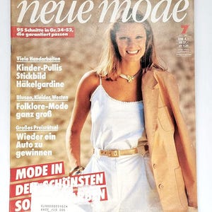 May include: A magazine cover featuring a woman wearing a white vest top, white trousers, and a brown blazer. The magazine is titled "neue mode" and features the text "95 Schnitte in Gr. 34-52, die garantiert passen" and "Viele Handarbeiten Kinder-Pullis Stickbild Häkelgardine Blusen, Kleider, Westen Folklore-Mode ganz groß Großes Preisrätsel Wieder ein Auto zu gewinnen MODE IN DER SCHÖNSTEN SO".