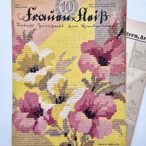 Puede incluir: Portada de revista de bordado vintage en alemán, con un diseño floral de flores rosas y amarillas. El título "Frauen Fleiß" y "10 Jahre" son visibles. Una segunda página con un patrón está en el fondo.