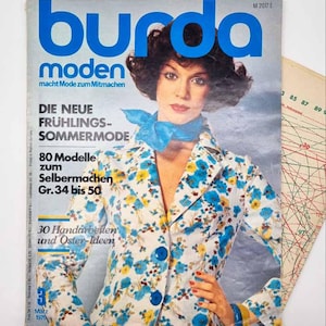 May include: A vintage Burda Moden magazine cover from March 1975, featuring a woman in a floral jacket with blue and yellow flowers. The magazine title is in large blue letters. The cover includes text about spring and summer fashion and dressmaking patterns.