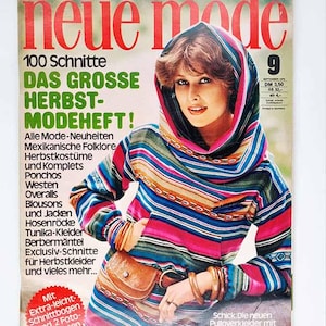May include: A vintage magazine cover with a woman in a striped hooded top. The title "Neue Mode" is in red. The cover text includes "Herbst-Modeheft!" and "Pulloverkleider mit Kapuzenkragen!", indicating autumn fashion trends. The magazine is in German.
