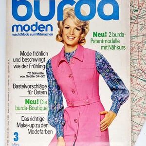 May include: A vintage Burda Moden magazine cover from March 1971, featuring a woman wearing a pink dress with a blue floral print vest. The cover text reads "Burda Moden macht Mode zum Mitmachen" and "Neu! 2 burda-Patentmodelle mit Nähkurs".