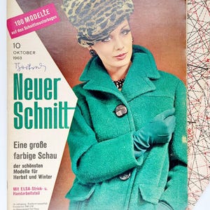 May include: A vintage sewing pattern cover featuring a woman wearing a green coat with large buttons, a leopard print hat, and black gloves. The cover text reads "100 Modelle auf den Schnittmusterbogen" and "Neuer Schnitt".