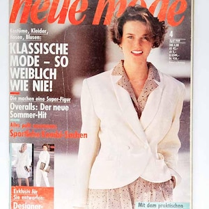 May include: Magazine cover featuring a woman in a white blazer and patterned dress. The magazine title is "Neue Mode" in red, with German text below. Additional text includes "Klassische Mode - So Weiblich Wie Nie!" and "Designer Schnitte von Nino Cerutti."