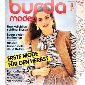 May include: A vintage fashion magazine cover featuring a woman in a striped blouse and brown vest. The magazine title "burda moden" is in large red letters. Text includes "ERSTE MODE FÜR DEN HERBST" and other German text. Sewing patterns are in the background.