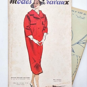 Puede incluir: Portada de la revista "Modes & Travaux" vintage con una ilustración de moda de una mujer con abrigo rojo, guantes blancos y sombrero. La portada de la revista tiene texto en francés y es de abril de 1954.