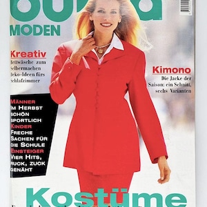 Può includere: Una copertina di rivista con una donna in completo rosso e camicia bianca. La rivista è "Burda Moden" con testo in tedesco. La copertina presenta testo sulla moda e il numero dell'edizione 8/95.