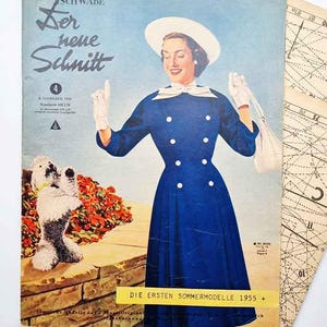 Op de afbeelding: Vintage magazine cover met een vrouw in een blauwe jurk en witte hoed. De cover heeft Duitse tekst, waaronder "Der neue Schnitt" en "Die ersten Sommermodelle 1955 +." Een kleine hond is ook afgebeeld.