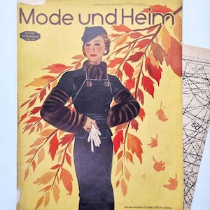 May include: A vintage Mode und Heim magazine cover featuring an illustration of a person in a dark blue outfit with fur accents and a matching hat, set against a yellow background with red and orange autumn leaves and white gloves.