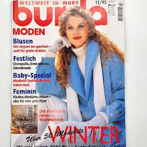 May include: A magazine cover featuring a woman with red hair wearing a blue jacket and white turtleneck. The magazine title is "Burda Moden" with text in German. The cover also includes the word "WINTER" in large red letters.