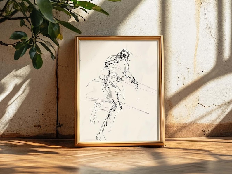 May include: A framed black and white sketch of a figure in motion. The artwork is in a gold frame, set against a textured wall and wooden floor. The drawing style is loose and expressive, with visible lines.