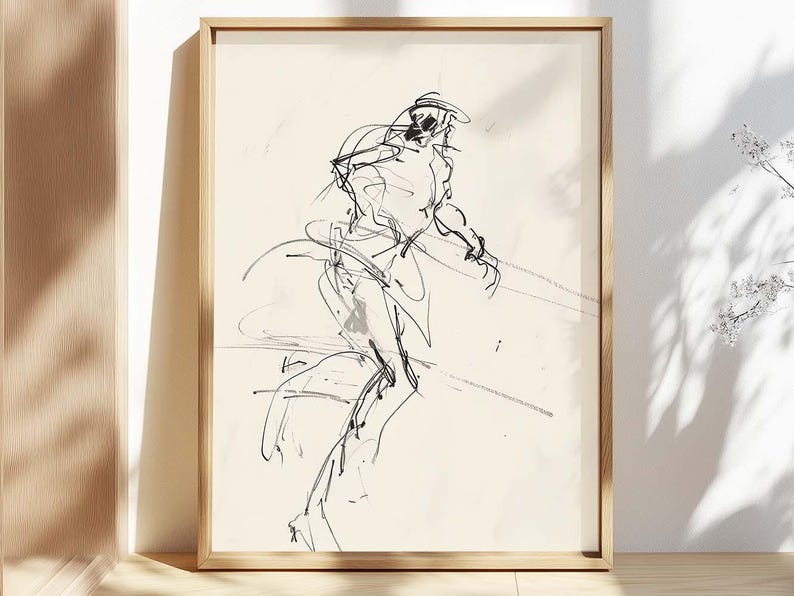 May include: A framed black and white sketch of a figure in motion. The artwork features loose, expressive lines, creating a dynamic and abstract representation. The frame is a light wood color, adding a natural touch to the piece.