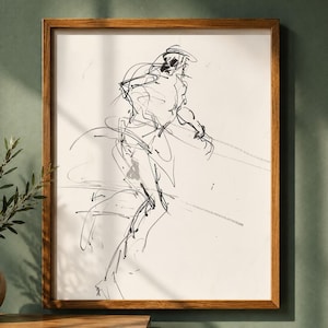 May include: A framed black and white sketch of a person in motion. The artwork is a minimalist line drawing with a wooden frame. The piece is displayed on a wall next to a vase with greenery.