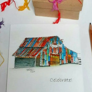 May include: Watercolor painting of a colorful barn with the text "Barn Dance" and "Celebrate!". The barn has a red, blue, and orange roof and multi-colored walls. A small brown gift box with colorful ribbons and feathers sits above the painting.
