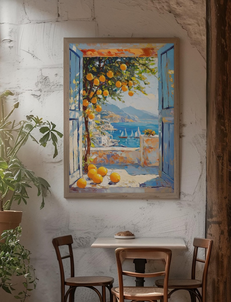 May include: A framed painting depicts a coastal scene with a window view. The painting shows a tree with yellow fruit, blue shutters, and a view of the sea with sailboats. The painting is displayed on a textured white wall, with a table and chairs in front.