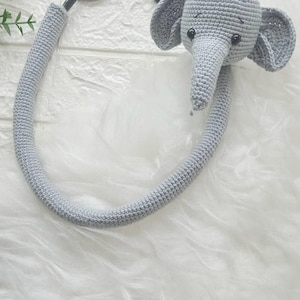 May include: A gray crocheted elephant toy attached to a stethoscope. The stethoscope is made of metal and has a gray crocheted covering.
