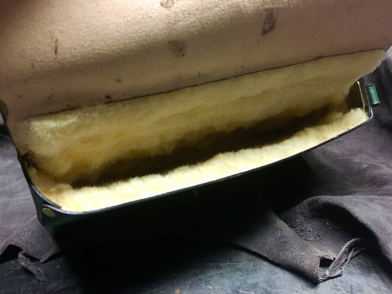 May include: A black leather case with a soft, white, fluffy lining. The case is open and the lining is visible.