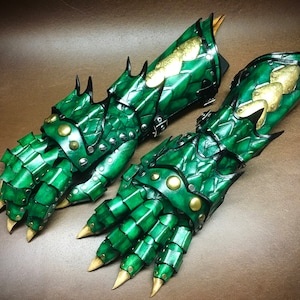 May include: A pair of green leather gauntlets with gold accents and spikes. The gauntlets are designed to look like dragon claws.