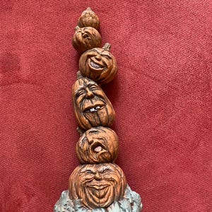 Könnte beinhalten: Ein Stapel aus fünf Keramikkürbissen mit verschiedenen Gesichtsausdrücken. Die Kürbisse sind in Braun- und Orangetönen bemalt und haben einen rustikalen, handbemalten Look.