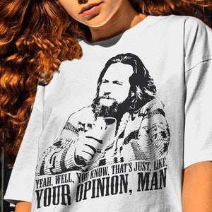 May include: White t-shirt featuring a black and white image of a man holding a cup. The text on the shirt reads "YEAH, WELL, YOU KNOW, THAT'S JUST, LIKE, YOUR OPINION, MAN".