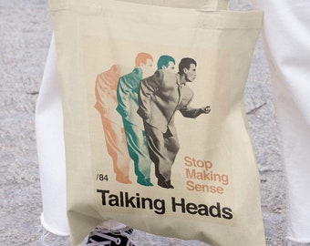 May include: A beige canvas tote bag featuring a graphic of three men in suits and the text "Stop Making Sense" and "Talking Heads".