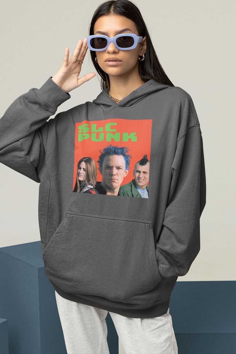 Op de afbeelding: Een donkergrijze hoodie met een grafische print van een band genaamd "SLC PUNK". De bandleden zijn afgebeeld op de print, waarbij een lid blauw haar heeft.