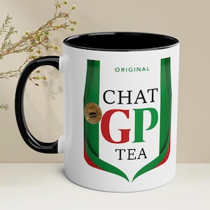 Könnte beinhalten: Weiße Keramiktasse mit schwarzem Rand und Henkel. Die Tasse zeigt ein grünes, rotes und weißes Logo mit dem Text "ORIGINAL CHAT GP TEA".