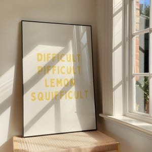Könnte beinhalten: Ein gerahmter Druck mit den Worten "Difficult, Piffifficult, Lemon, Squiffifficult" in gelber Schrift auf weißem Hintergrund.