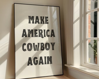 May include: A black framed poster with white background and black text that reads "Make America Cowboy Again".