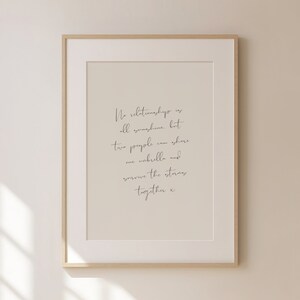 Op de afbeelding: Een ingelijst print met een beige achtergrond en zwarte tekst die luidt: "Geen enkele relatie is alleen maar zonneschijn, maar twee mensen kunnen een paraplu delen en de stormen samen overleven x".