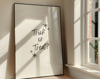 Puede incluir: Una impresión enmarcada en negro con el texto "Trick or Treat?" en letras blancas con estrellas a cada lado del texto. La impresión está colgada en una pared blanca.