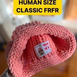 May include: A pink knitted beanie with a patch that says "Dog We Hat Ya!" in white text on a red background. The patch also says "Literally Just The Classic" in smaller white text.